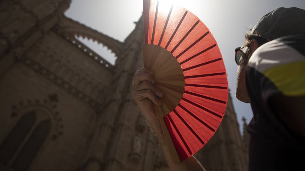 ARCHIV - Eine Frau kühlt sich auf Mallorca mit einem Fächer ab. Foto: Clara Margais/dpa/Archivbild