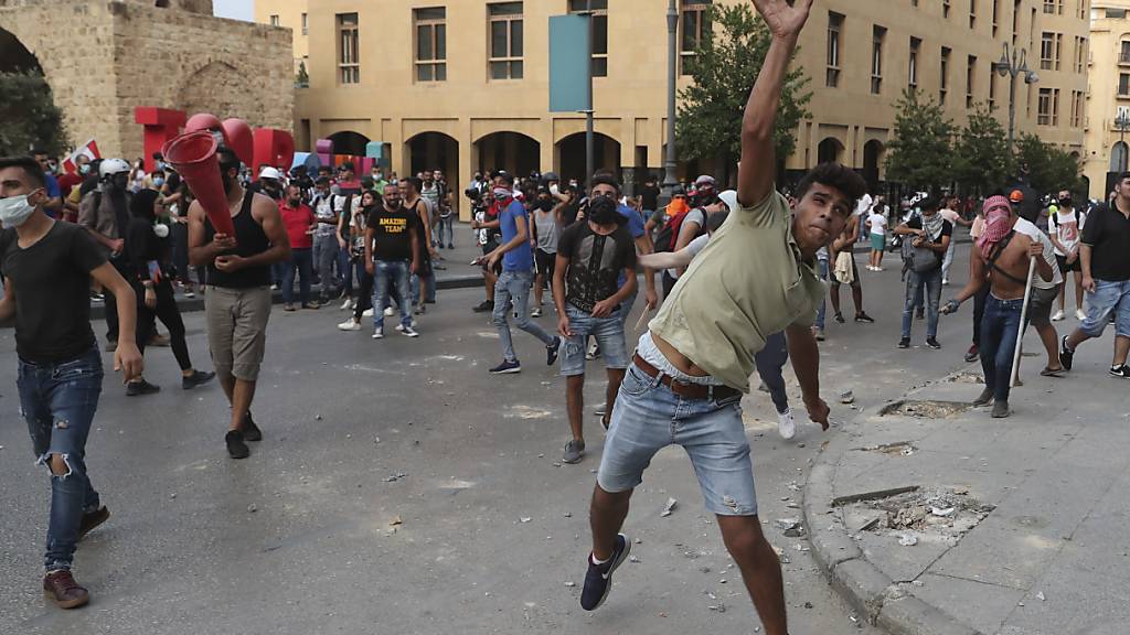 Demonstranten werfen bei einem regierungskritischen Protest in der Nähe des Parlamentsplatzes in Beirut Steine in Richtung der Bereitschaftspolizei. Foto: Bilal Hussein/AP/dpa
