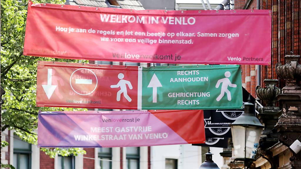 ARCHIV - Banner informieren in der Innenstadt von Venlo über die Einschränkungen. Foto: David Young/dpa