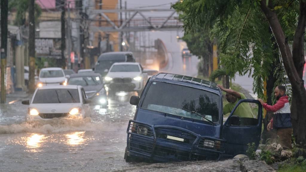 dpatopbilder - Menschen verlassen ein Auto auf einer unpassierbaren Straße, die durch die Regenfälle des Tropensturms Melissa überflutet wurde. Foto: Ricardo Hernandez/AP/dpa