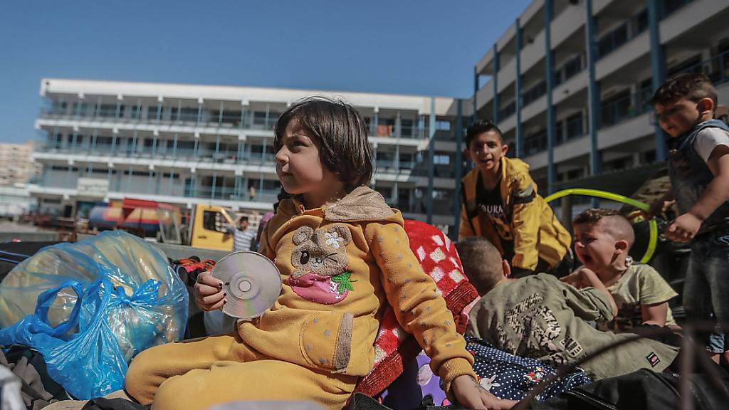Palästinenser sitzen mit ihren Habseligkeiten vor einer UN-Schule, in der sie Schutz suchen. Sie mussten während der israelischen Luftangriffe aus ihren Häusern fliehen inmitten des eskalierenden Aufflammens der israelisch-palästinensischen Gewalt. Foto: Mohammed Talatene/dpa