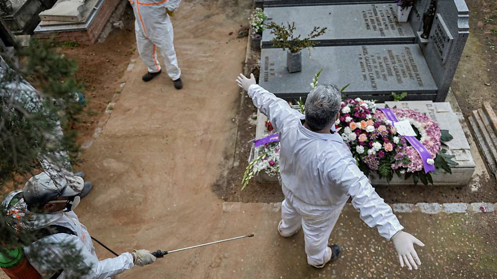 Desinfizieren auf dem Friedhof: Ein städtischer Angestellter desinfiziert einen Kollegen nach einer Beerdigung in Guadalajara.