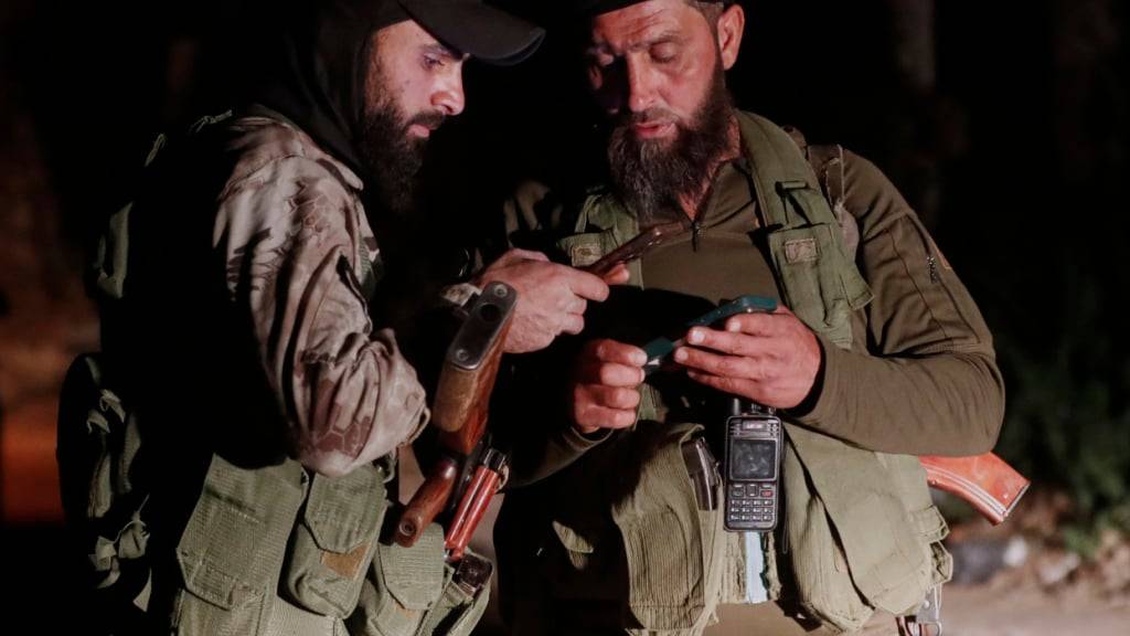 ARCHIV - Syrische Sicherheitskräfte überprüfen ihre Mobiltelefone an einem Kontrollpunkt, nachdem sie sich mit drusischen Bewaffneten darauf geeinigt haben, in der Umgebung von Jaramana, einem Vorort von Damaskus, in dem es Anfang der Woche zu Kämpfen gekommen war, zu stationieren. Foto: Omar Sanadiki/AP/dpa