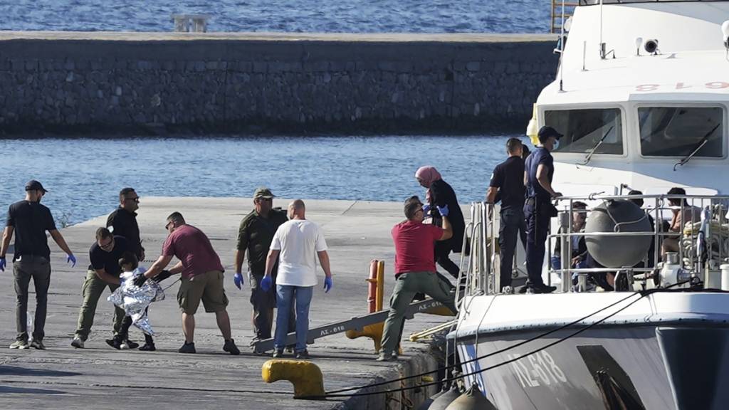 Ein Kind, das von Beamten der Küstenwache eskortiert wird, geht nach einer Rettungsaktion im Hafen von Mytilene mit anderen Migranten von Bord eines Schiffes. Fünf Migranten sind bei dem Versuch ums Leben gekommen, von der Türkei in Schlauchbooten zu den griechischen Inseln Lesbos und Samos überzusetzen. Foto: Panagiotis Balaskas/AP/dpa