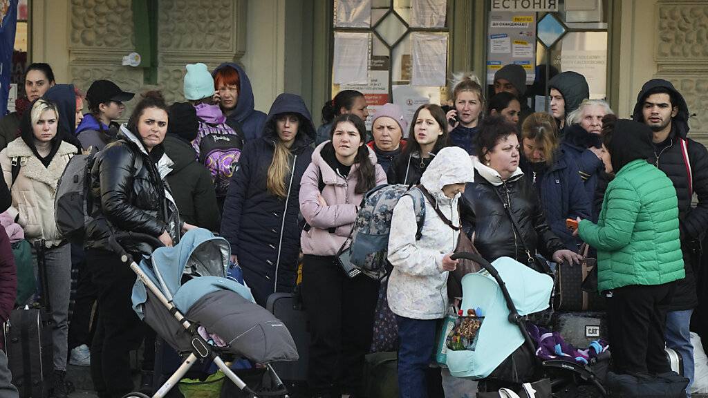 Flüchtlinge aus der Ukraine warten auf einem Bahnhof auf einen Transport. Foto: Sergei Grits/AP/dpa