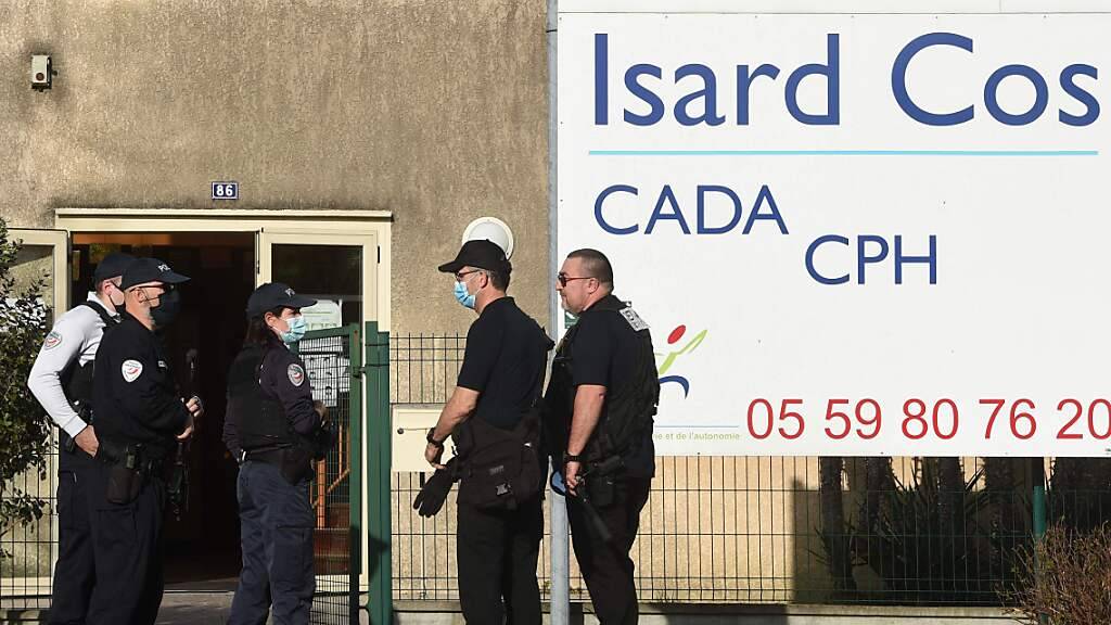 Polizeibeamte stehen vor dem Eingang des Isard Cos Aufnahmezentrums für Geflüchtete (CADA), in dem ein Mann mit einem Messer getötet worden sein soll. Foto: Gaizka Iroz/AFP/dpa