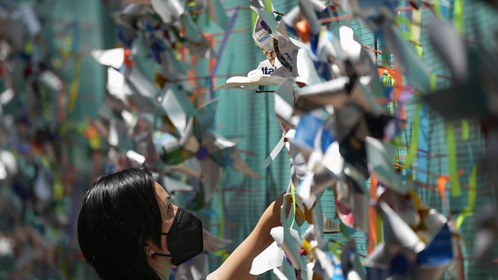 Eine Frau hängt während einer Gedenkveranstaltung Stecknadelräder im Gedenken an Corona-Opfer an eine Wand in Sao Paulo. (Archivbild) Foto: Andre Penner/AP/dpa