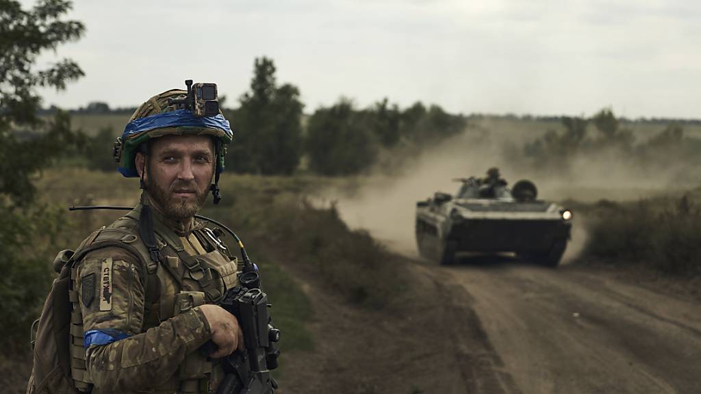 Ein Soldat der 3. Separatistenbrigade der Ukraine steht an einer Straße, hinter ihm fährt ein Schützenpanzer. Die Region um Bachmut ist Schauplatz heftiger Kämpfe mit den russischen Streitkräften. Foto: LIBKOS/AP