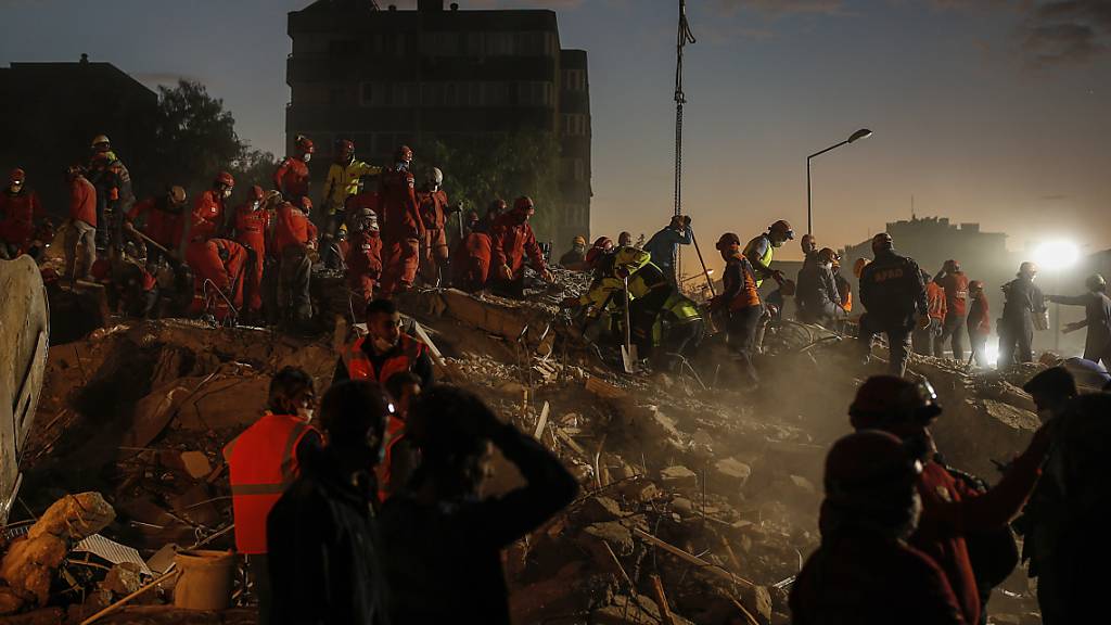 Mitglieder des Rettungsdienstes suchen in den Trümmern eines eingestürzten Gebäudes in Izmir nach Überlebenden. Foto: Darko Bandic/AP/dpa