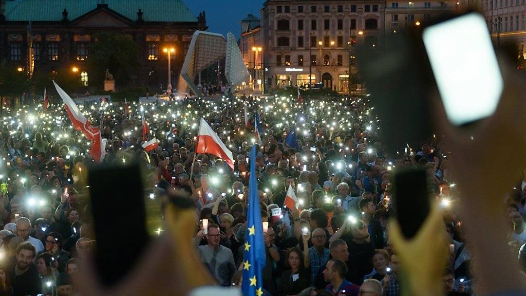 Mit Kerzen und Handylicht: In mehreren Städten gehen Polen am Sonntag auf die Strasse, um gegen die Justizreform zu protestieren.