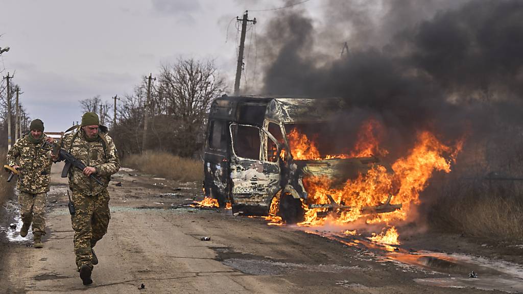 HANDOUT - Auf diesem von der ukrainischen 10. Gebirgsjägerbrigade «Edelweiß» zur Verfügung gestellten Foto gehen ukrainische Soldaten an einem Bus vorbei, der nach Drohnenangriff in der Nähe von Bachmut in der Region Donezk brennt. Foto: Shandyba Mykyta/10th Mountain Assault Brigade "Edelweiss"7ap/dpa - ACHTUNG: Nur zur redaktionellen Verwendung im Zusammenhang mit der aktuellen Berichterstattung und nur mit vollständiger Nennung des vorstehenden Credits
