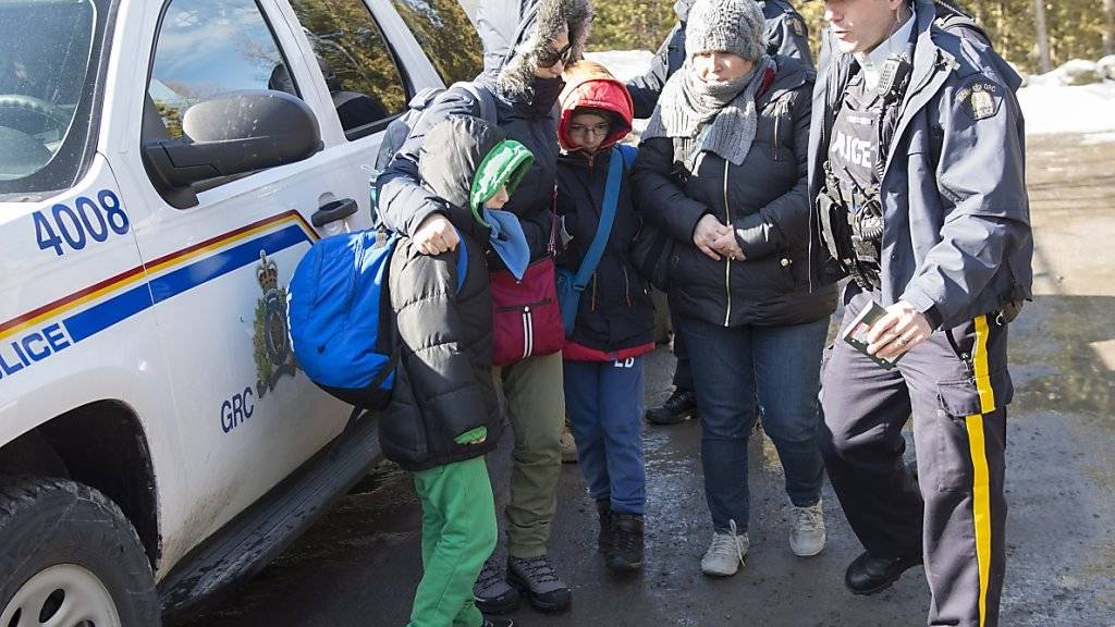 Kanadische Polizisten nehmen eine Familie von Asylsuchenden an der Grenze zu den USA in Hemmingford in Empfang.