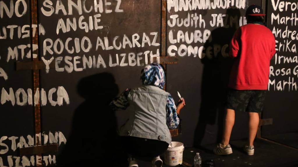 Frauen bemalen die Metallbarrieren des Nationalpalastes mit Namen von Opfern von Femiziden. Vor geplanten Protesten am Weltfrauentag haben Aktivistinnen einen langen Zaun vor dem Präsidentenpalast in Mexiko-Stadt mit Namen von ermordeten Frauen voll geschrieben.