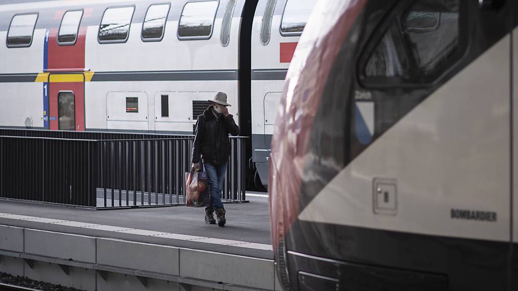 Ein Mann mit Maske auf dem Weg zum Zug am Bahnhof in St. Gallen. (Archivbild)
