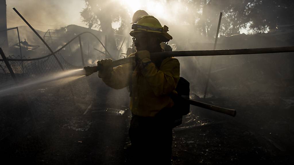 HANDOUT - Ein Feuerwehrmann aus Colorado Springs, Kalifornien, spritzt Wasser auf ein beschädigtes Gebäude. Foto: Stephen Lam/San Francisco Chronicle/AP/dpa - ACHTUNG: Nur zur redaktionellen Verwendung im Zusammenhang mit einer Berichterstattung und nur mit vollständiger Nennung des vorstehenden Credits