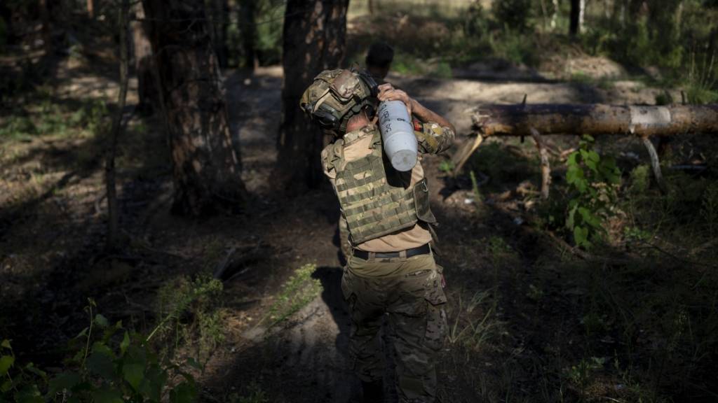 Ein ukrainischer Soldat trägt eine Granate in Richtung einer Haubitze an der Frontlinie bei Lyman. Foto: Bram Janssen/AP/dpa