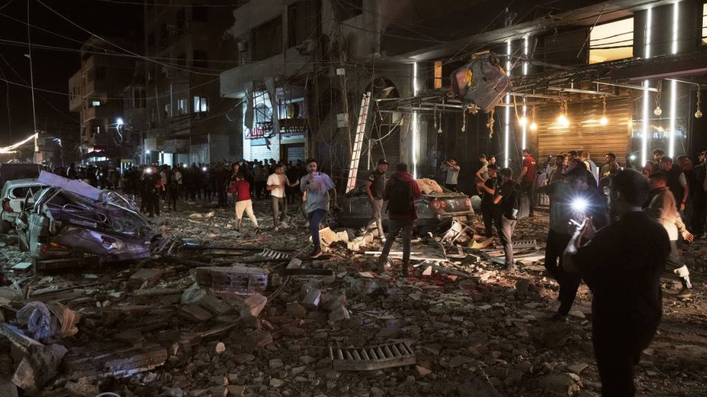 dpatopbilder - Palästinenser inspizieren den Ort eines israelischen Luftangriffs. Foto: Jehad Alshrafi/AP/dpa