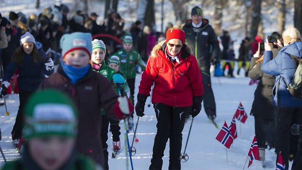 Die norwegische Königin Sonja gleitet gemeinsam mit vielen Kindern auf Langlaufskiern über den Schlossplatz, auf dem zum 25. Thronjubiläum eine riesige Wintersportlandschaft entstand.