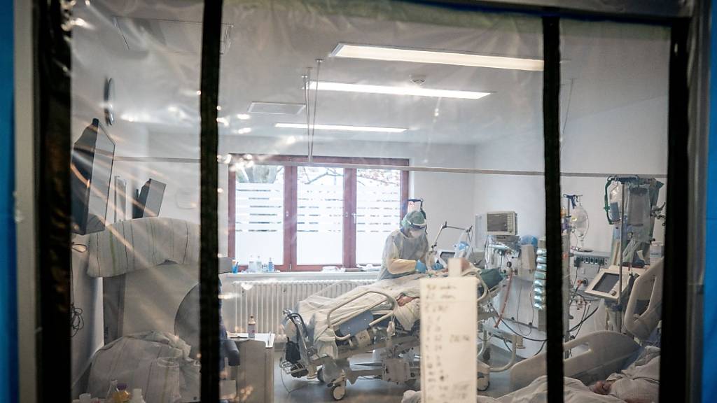 ARCHIV - Ein Intensivpfleger betreut hinter einer Schleuse auf der Intensivstation des Krankenhauses Bethel in Berlin einen Corona-Patienten. Foto: Kay Nietfeld/dpa