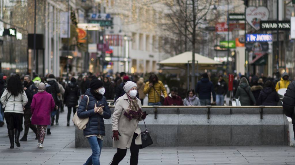 Zwei Personen mit Mund-Nasen-Schutz gehen über eine Einkaufsstraße. Seit November gelten in Österreich Coronabeschränkungen für ungeimpfte Bürgerinnen und Bürger. Foto: Michael Gruber/AP/dpa
