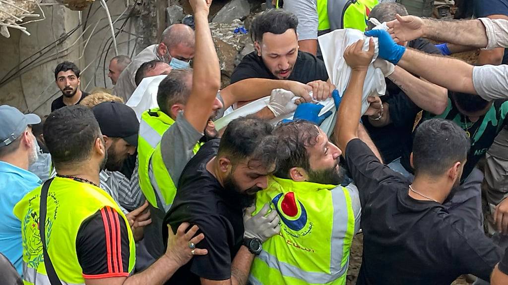 Rettungskräfte tragen eine Leiche am Ort eines Raketeneinschlags in den südlichen Vororten von Beirut. Foto: Bilal Hussein/AP/dpa