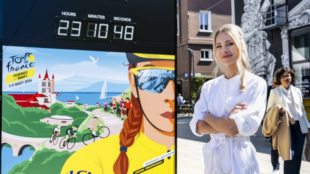 Marion Rousse, die Direktorin der Tour de France Femmes, steht neben der Affiche für die Austragung 2026 mit dem Countdown in Lausanne