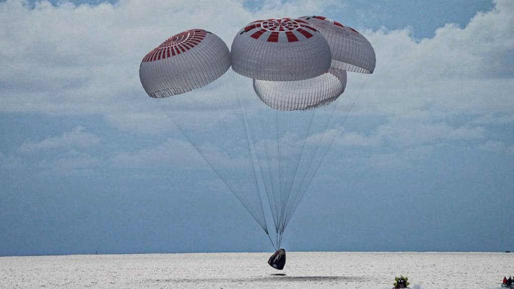 Eine SpaceX-Kapsel mit vier Personen an Bord geht vor der Küste Floridas mit Fallschirmen in den Atlantik nieder. Foto: Uncredited/SpaceX via AP/dpa - ACHTUNG: Nur zur redaktionellen Verwendung und nur mit vollständiger Nennung des vorstehenden Credits bis 14 Tage nach Sendedatum.