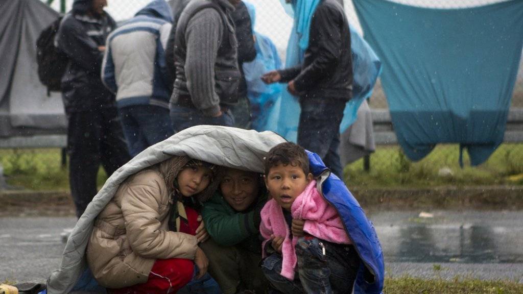 Kinder schützen sich bei der Grenze Sredisce ob Dravi in Slowenien vor dem Regen.