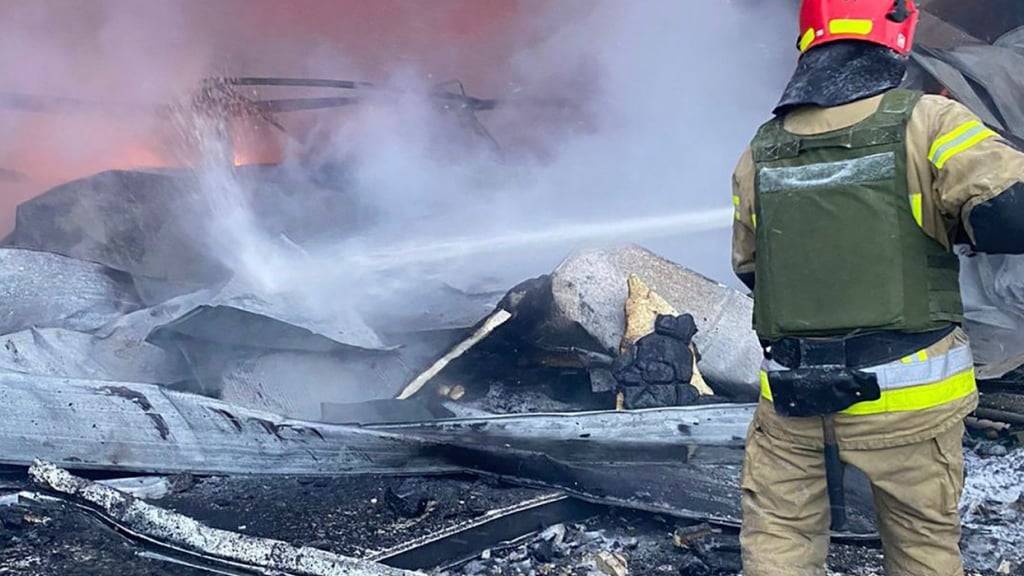 HANDOUT - Ein Feuerwehrmann löscht ein Feuer nach einem russischen Angriff. Das Foto stellte der ukrainische Katastrophenschutz zur Verfügung. Foto: Uncredited/Ukrainian Emergency Service/AP/dpa - ACHTUNG: Nur zur redaktionellen Verwendung im Zusammenhang mit dem genannten Text und nur bei vollständiger Nennung des vorstehenden Credits