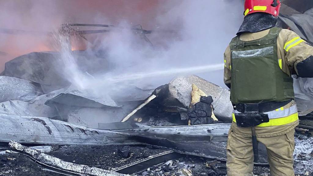 HANDOUT - Ein Feuerwehrmann löscht ein Feuer nach einem russischen Angriff. Das Foto stellte der ukrainische Katastrophenschutz zur Verfügung. Foto: Uncredited/Ukrainian Emergency Service/AP/dpa - ACHTUNG: Nur zur redaktionellen Verwendung im Zusammenhang mit dem genannten Text und nur bei vollständiger Nennung des vorstehenden Credits