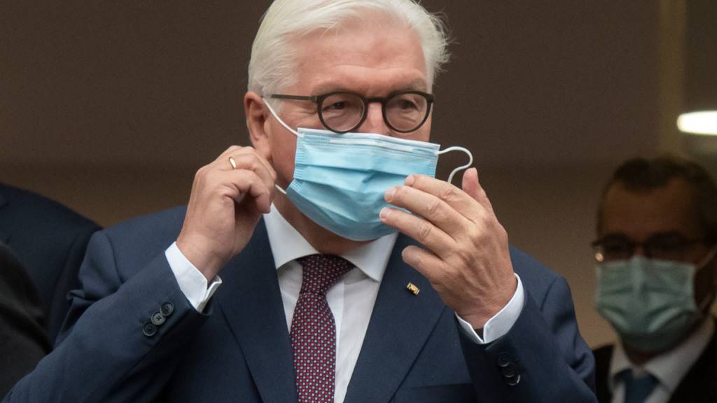 ARCHIV - Bundespräsident Frank-Walter Steinmeier steht vor einem Gebäude der Uniklinik und nimmt für ein Gruppenfoto seine Maske ab. Foto: Bernd Thissen/dpa