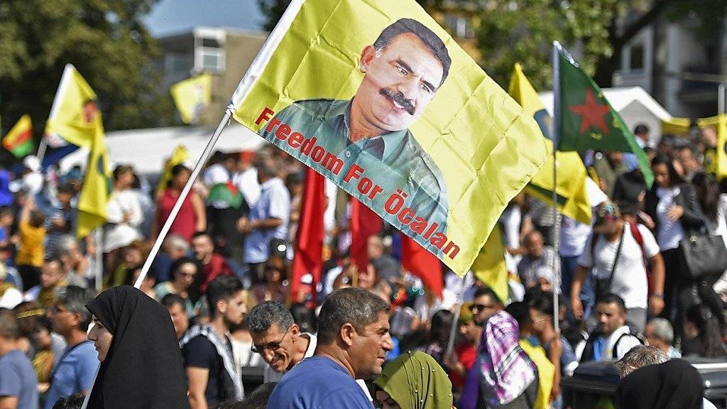Eine Demonstrantin hält in Köln eine Öcalan-Flagge hoch.