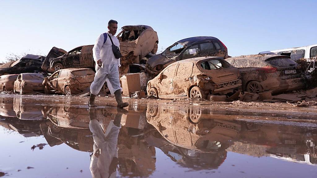 dpatopbilder - Ein Mann geht an aufgestapelten Autos vorbei, nachdem die Überschwemmungen in Catarroja in der Region Valencia in Spanien Verwüstungen und Hunderte von Toten und Vermissten hinterlassen haben. Foto: Alberto Saiz/AP