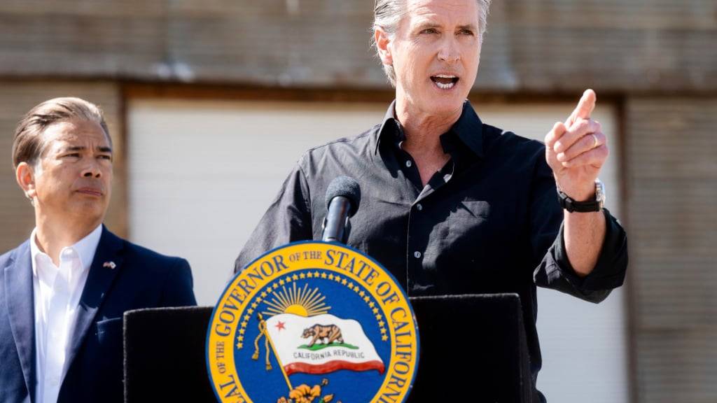 ARCHIV - Gavin Newsom, Gouverneur von Kalifornien, erörtert die Zölle von Präsident Donald Trump, während der Generalstaatsanwalt von Kalifornien, Rob Bonta (l) bei der Pressekonferenz auf einer Mandelfarm zuhört. Foto: Noah Berger/AP/dpa