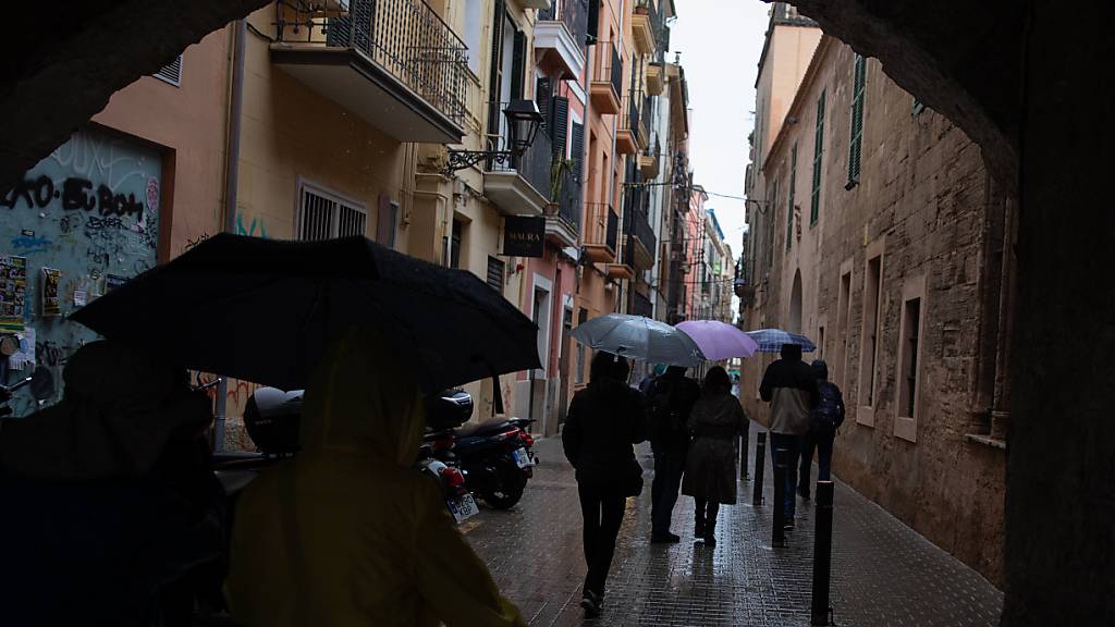 Menschen spazieren mit Regenschirmen in der Innenstadt von Palma an einem regnerischen Tag. Foto: Clara Margais/dpa