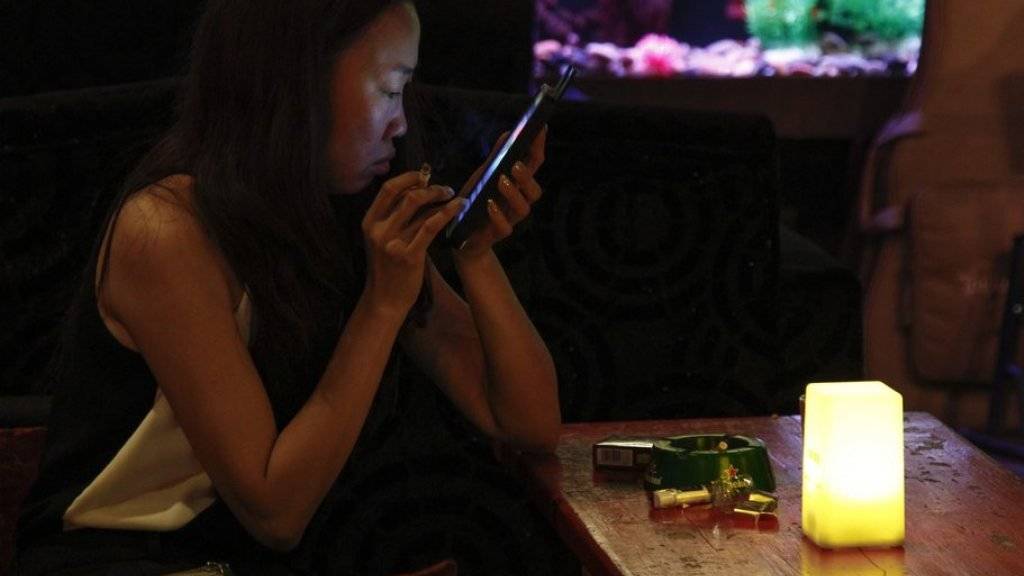 Eine Chinesin hält in einer Pekinger Bar eine Zigarette in der Hand und schaut auf ihr Smartphone. Gemäss der Studie in «The Lancet» waren unter den Raucher-Toten im Jahr 2010 neben 840'000 Männern auch 130'000 Frauen (Archiv)