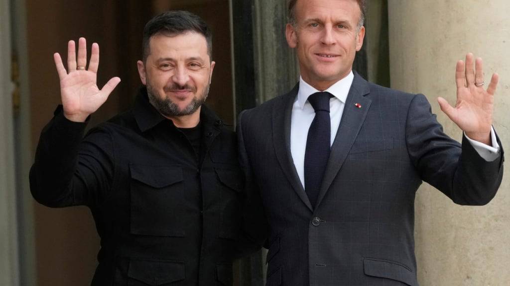 Der französische Präsident Emmanuel Macron (r) und Wolodymyr Selenskyj, Präsident der Ukraine, winken Journalisten vor einem Treffen im Elysee-Palast. Foto: Michel Euler/AP/dpa