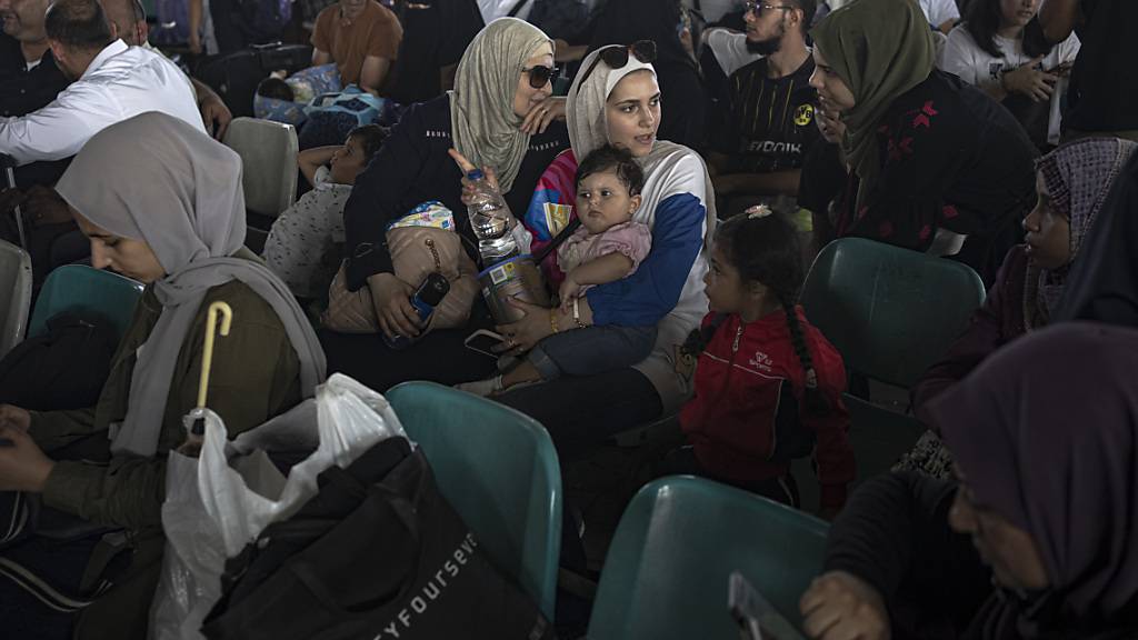 Menschen warten am Grenzübergang zwischen dem Gazastreifen und Ägypten. Verletzte Palästinenser und Inhaber ausländischer Pässe können über den Grenzübergang Rafah evakuiert werden. Foto: Fatima Shbair/AP/dpa