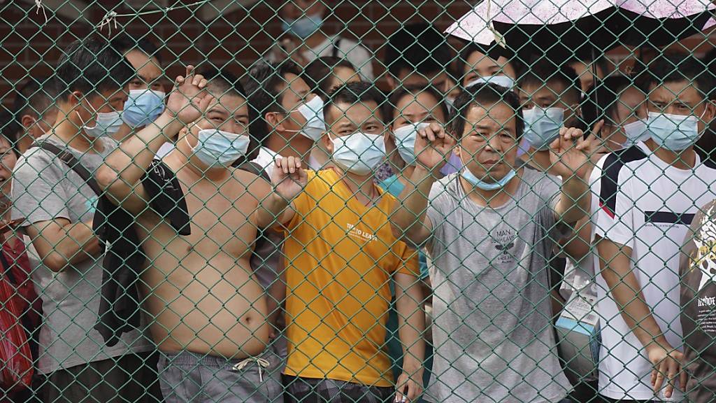 Anwohner warten hinter einem Zaun auf ihren Corona-Test. Nach einem Anstieg der Corona-Infektionen wurde ein Teil der südchinesischen Stadt Guangzhou gesperrt und die Bewohner wurden dazu aufgefordert, zu Hause zu bleiben, um auf das Coronavirus getestet zu werden. Foto: Uncredited/AP/dpa Foto: Uncredited/AP/dpa
