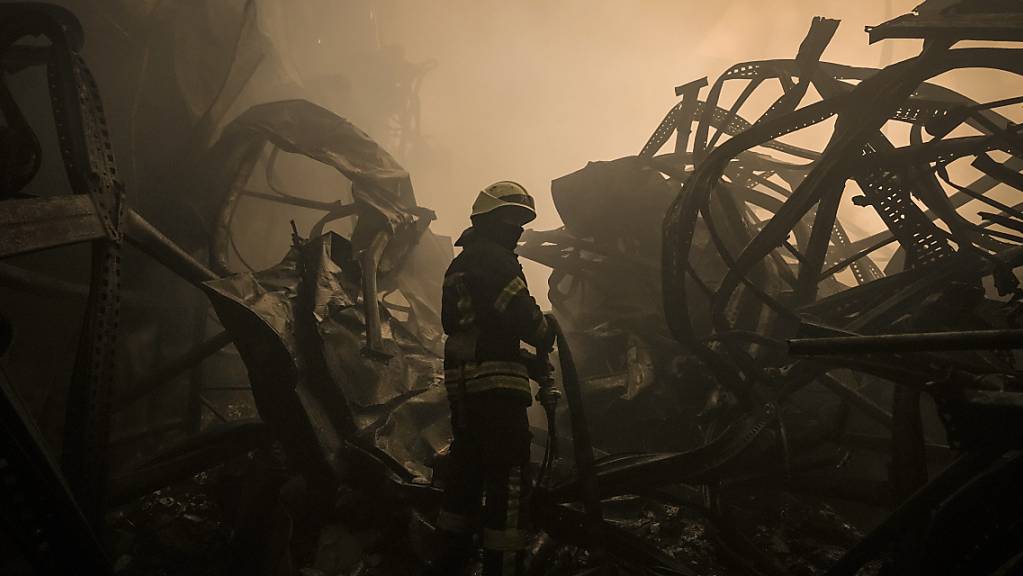 Ein ukrainischer Feuerwehrmann zieht einen Schlauch durch ein großes Lebensmittellager am Stadtrand von Kiew, das durch einen Luftangriff zerstört wurde. Foto: Vadim Ghirda/AP/dpa