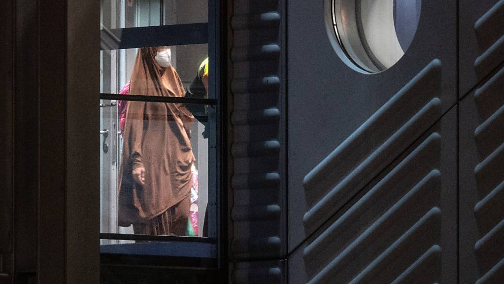 Eine verschleierte Frau mit einer Maske betritt aus der Gangway einer Chartermaschine heraus einen abgeschirmten Bereich der Bundespolizei am Flughafen Frankfurt. Foto: Boris Roessler/dpa