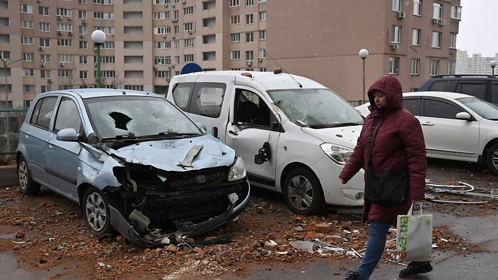 Eine Frau geht in Kiew nach einem russischen Dronenangriff am Freitag an beschädigten Autos vorbei. Foto: Sergei Chuzavkov/SOPA Images via ZUMA Press Wire/dpa