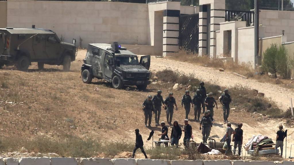 Israelische Soldaten stehen im besetzten Westjordanland im Dorf Kusra südlich von Nablus neben Siedlern Wache vor palästinensischen Häusern, die sie abgeriegelt haben. Foto: Nidal Eshtayeh/AP/dpa