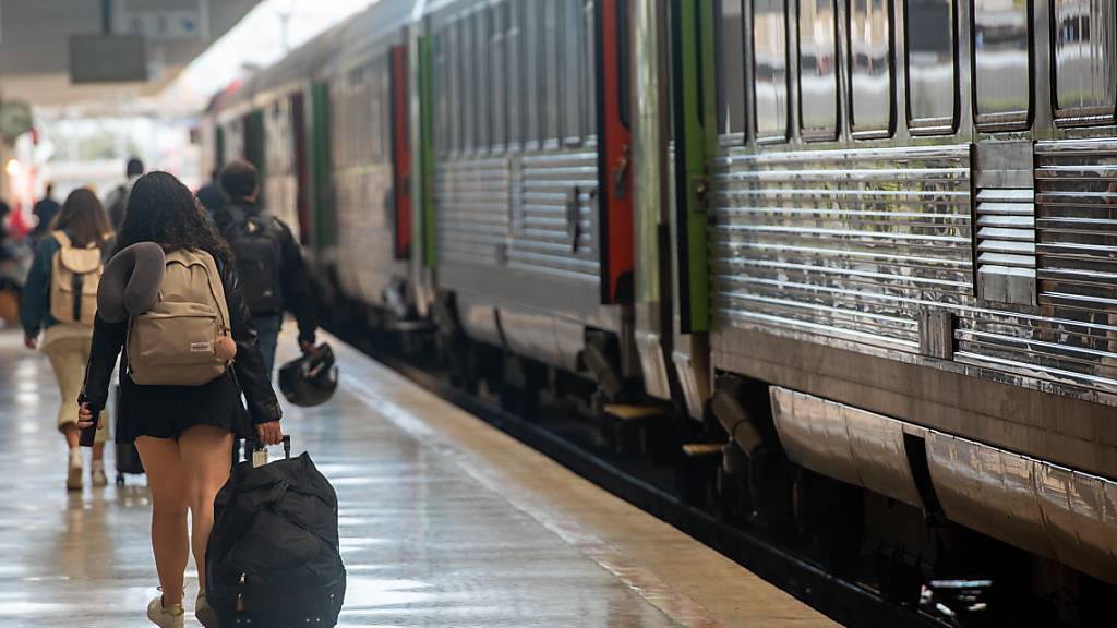 Menschen gehen im Bahnhof Santa Apolonia im Zentrum der portugiesischen Hauptstadt über einen Bahnsteig. Foto: Paulo Mumia/dpa