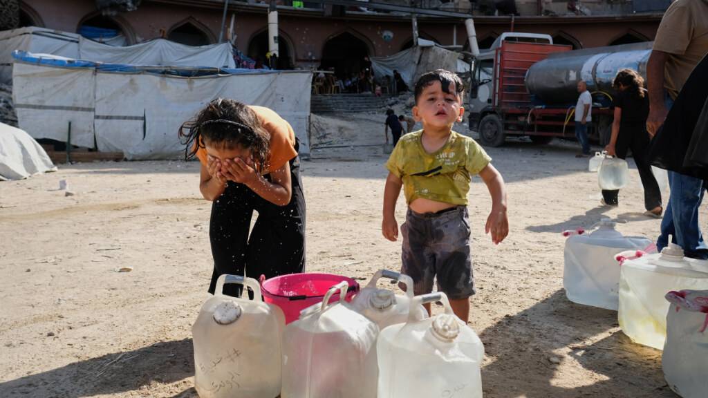 Vertriebene palästinensische Kinder kühlen sich in der Stadt Gaza in einem provisorischen Zeltlager mit Wasser ab. Foto: Jehad Alshrafi/AP/dpa