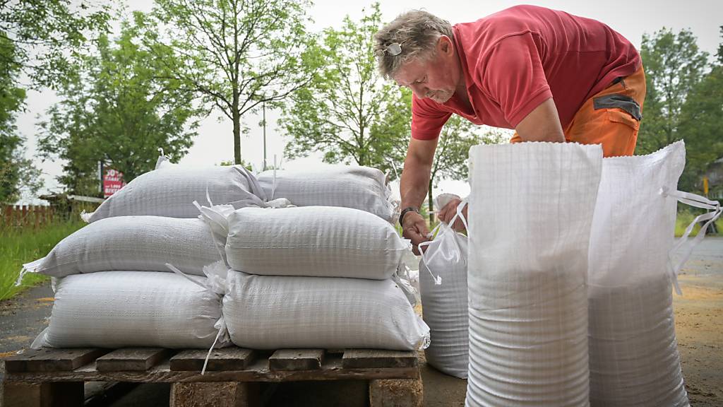 Uwe Gundermann, Mitarbeiter des Bauhof Chemnitz, bindet Sandsäcke zu und stapelt sie auf Paletten. Foto: Heiko Rebsch/dpa