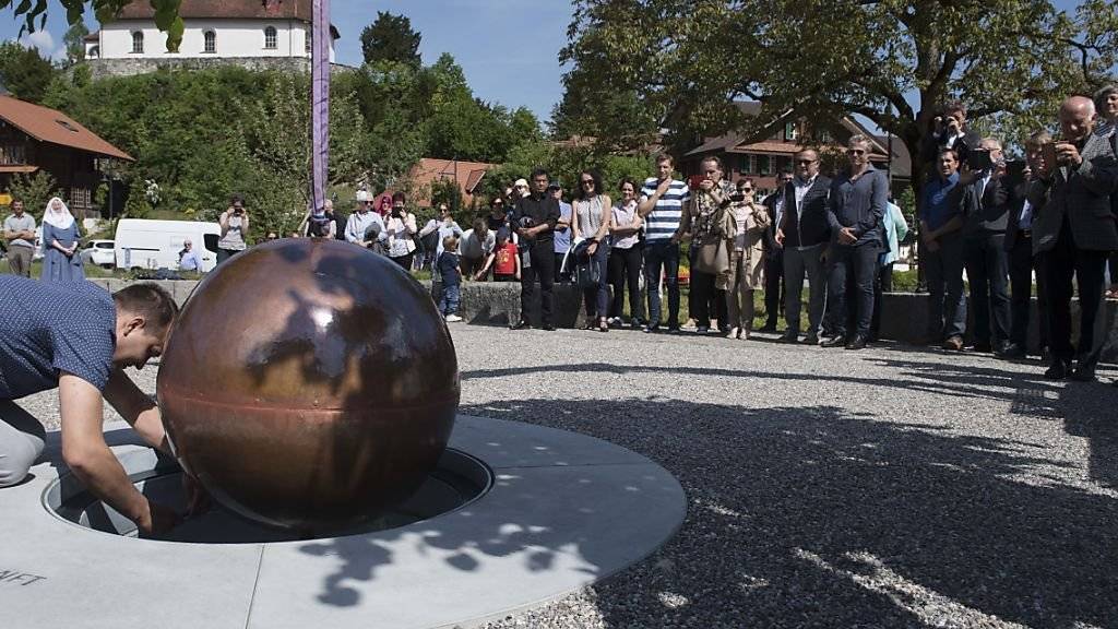 Die versiegelte Kupferkugel mit den Gedanken aus dem Bruder-Klaus-Gedenkjahr wird auf dem Dorfplatz von Flüeli in einen Schacht eingelassen.