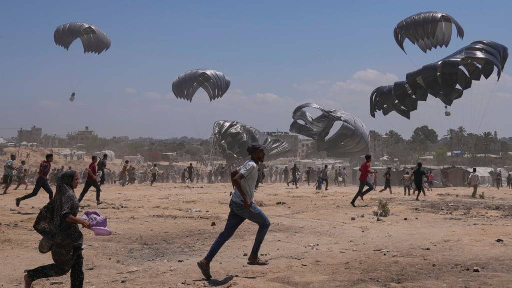 Palästinenser beeilen sich, humanitäre Hilfsgüter einzusammeln, die mit Fallschirmen im zentralen Gazastreifen abgeworfen wurden. Foto: Abdel Kareem Hana/AP/dpa