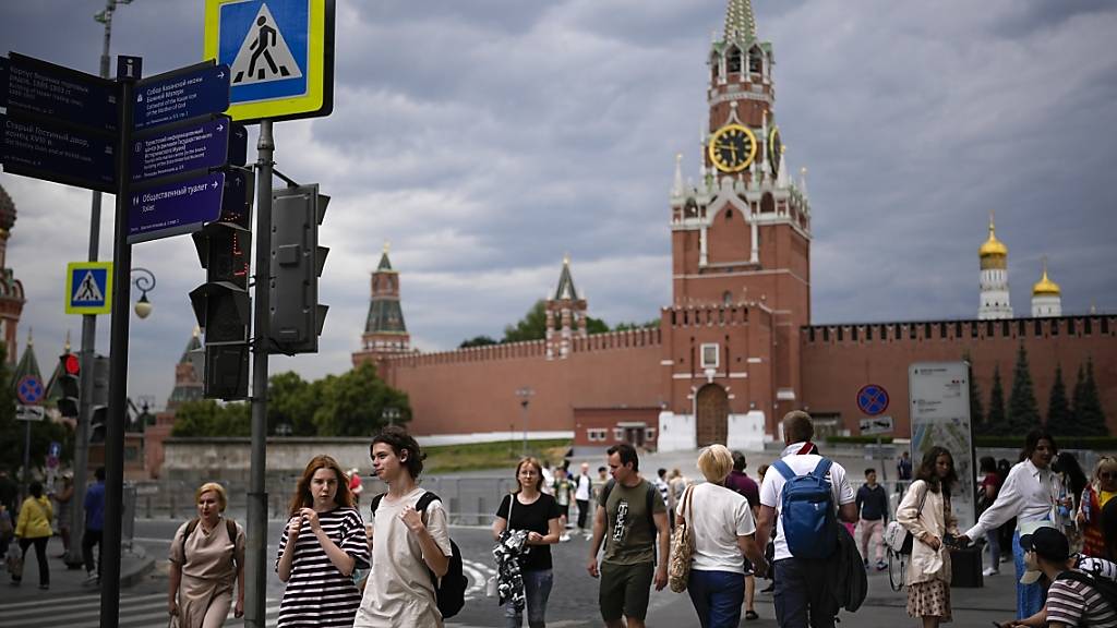 ARCHIV - Menschen gehen vor dem geschlossenen Roten Platz mit der Kremlmauer und dem Spasskaja-Turm im Hintergrund. Foto: Alexander Zemlianichenko/AP/dpa