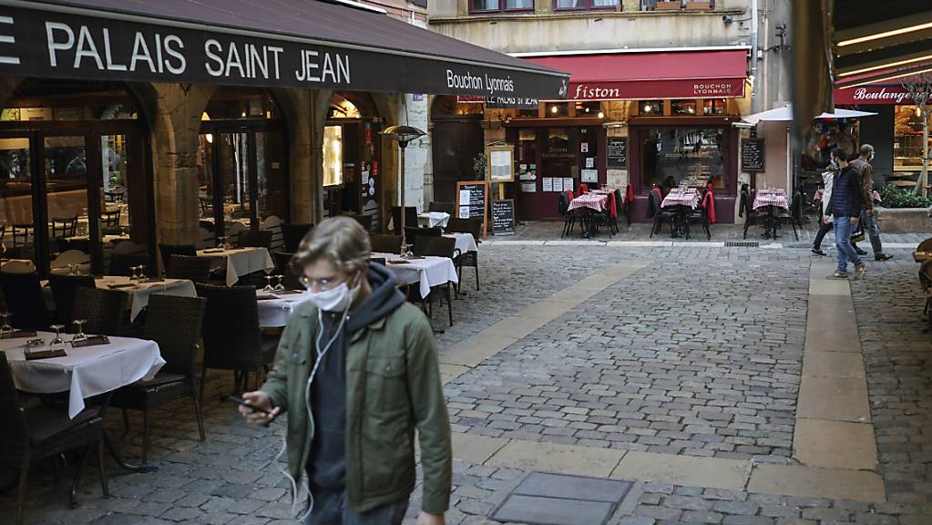 ARCHIV - Ein Mann trägt eine Maske und geht an den leeren Tischen und Stühlen von Restaurants vorbei. Die Corona-Pandemie hat in den fünf größten Volkswirtschaften Europas das Verbrauchervertrauen nachhaltig erschüttert. Foto: Laurent Cipriani/AP/dpa